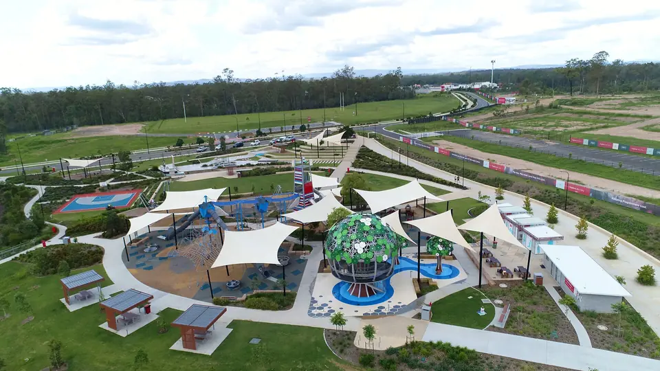 Aerial view of a large playground and park with shade sails in Flagstone.