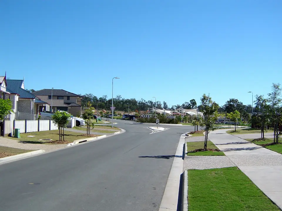 A wide new street with young trees and new houses in Yarrabilba.
