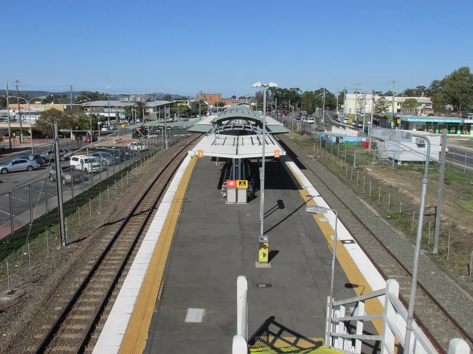 Woodridge railway station seen from the footbridge, with car parks and shops beyond.
